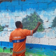 Derlan de Matos Almeida pintando o mural na Freguesia